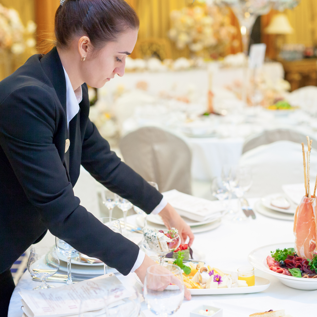 Eine Kellnerin deckt den Tisch ein