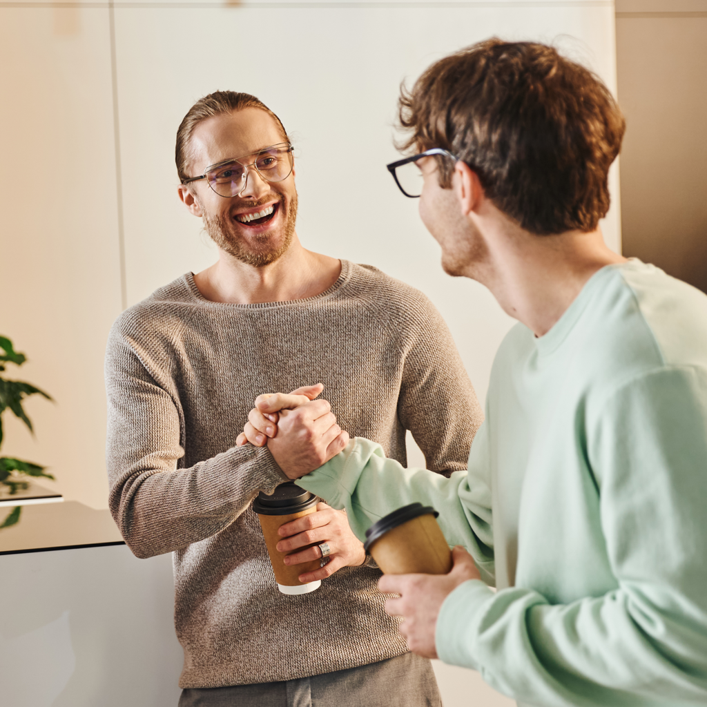 Zwei Männer geben sich die Hand und lachen fröhlich